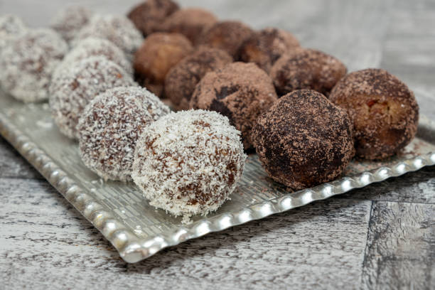 Coconut rum balls being covered with grated coconut on plate stock photo