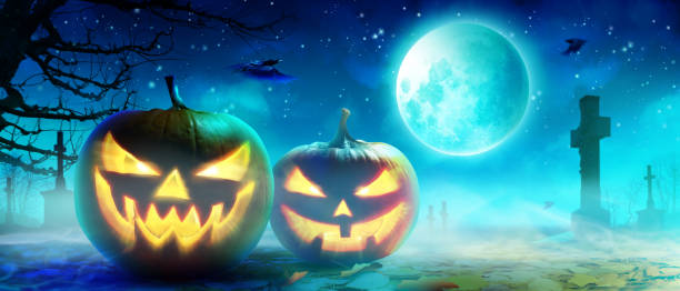 istock Halloween pumpkin face with burning fire inside in the graveyard. 1282560672