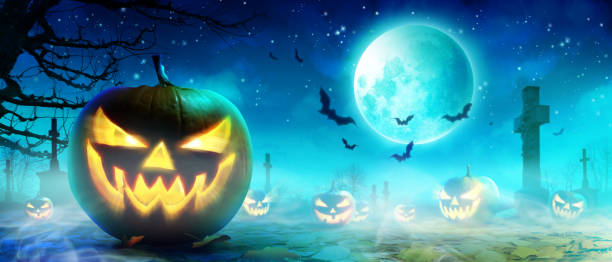 istock Halloween pumpkin face with burning fire inside in the graveyard. 1282560689