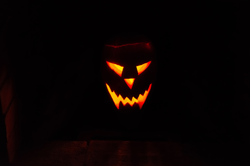 traditional glowing fiery Jack-o'-lantern face from a pumpkin with candle on a halloween