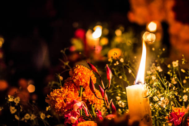 Day of the dead candle lit with flowers Candle lit with cempasúchil flowers around in the cemetery of Janitzio, Michoacan, Mexico mexican day of the dead stock pictures, royalty-free photos & images