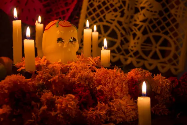Altar with sugar skull, bread of the dead and cempasuchil flowers, illuminated with candlelight