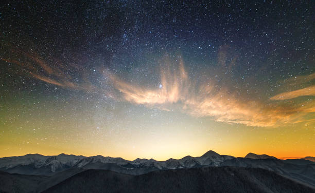 Amazing night mountain landscape with high peaks and bright starry sky above.