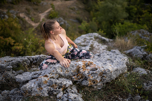 Close up shot of a blond beautiful girl free climbing a rock in nature and she is reaching the top of without any ropes or any other equipement.
