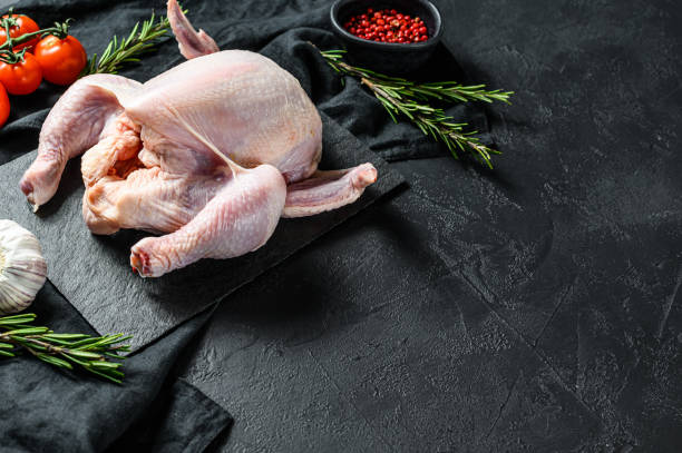 istock Raw whole chicken with rosemary and pink pepper. Black background. Top view. Space for text 1282567006