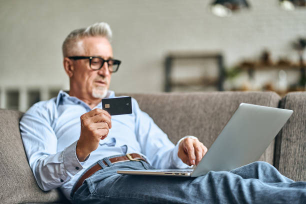 istock Adult man sitting on sofa while surfing the web and shopping online 1282567955