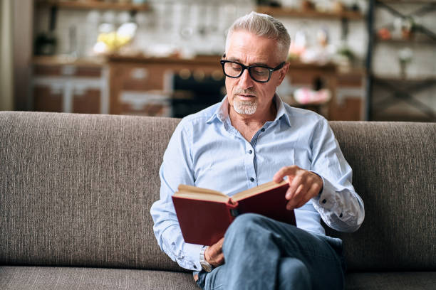 istock Attractive mature man reading book at home 1282567961