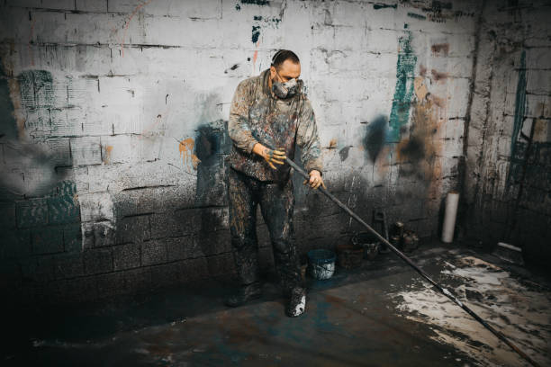 istock A man with a gas mask is holding a long paint roller in a messy room 1282568613