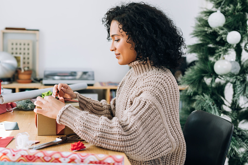 Getting Ready for Christmas: a Happy Young Woman Packing Christmas Presents for her Loved Ones