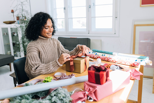 Getting Ready for Christmas: a Happy Young Woman Packing Christmas Presents for her Loved Ones (Copy Space)