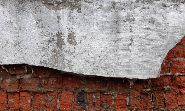 istock Destroyed gray plaster on a red brick wall. Background 1282572171