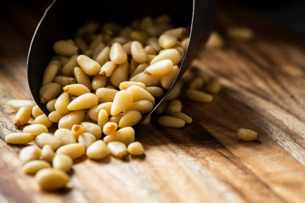 An antique metal scoop of raw pine nuts.