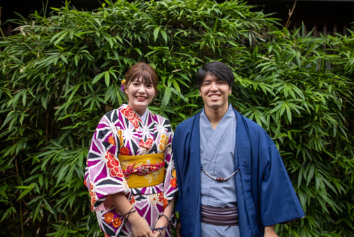 Portrait of young couple in kimono standing in front of ‘Sasa’ - green bamboo leaves