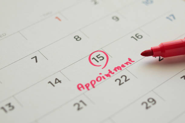 istock Red color marker pen pointing at important appointment schedule on white calendar page date close up 1282579265