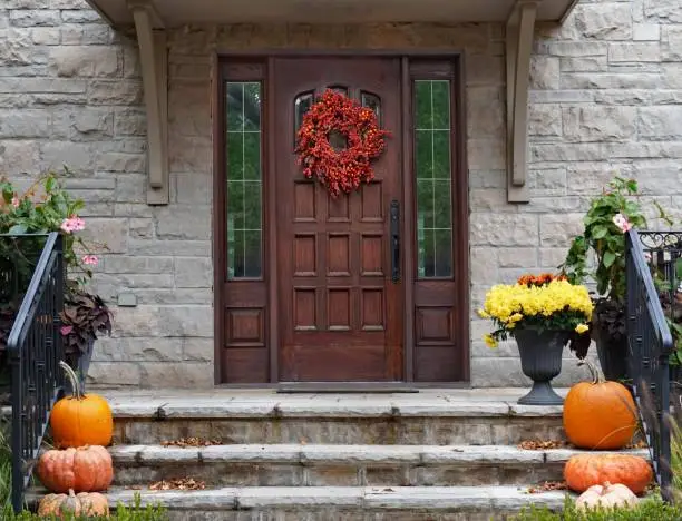 Photo of Front porch of house with Halloween decorations and wreath on wooden front door