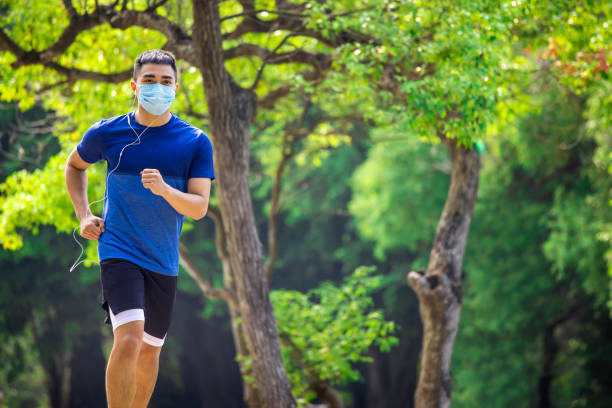istock young man in face mask and jogging in the park during quarantine 1282584771