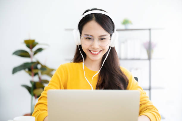istock Young asian woman in headphone having conversation chatting while using laptop at house. Work at home, Video conference, Online meeting video call, Virtual meetings, Remote learning and E-learning 1282587093