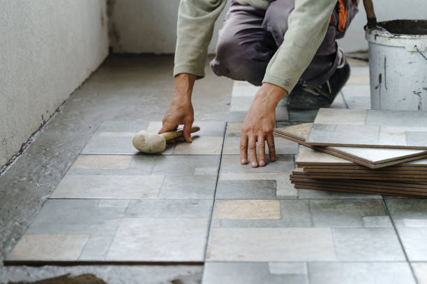 istock Close up on hands of unknown senior man craftsman using hammer to adjust and lay ceramic tiles on the balcony or terrace over adhesive cement in day - construction industry concept copy space 1282588101