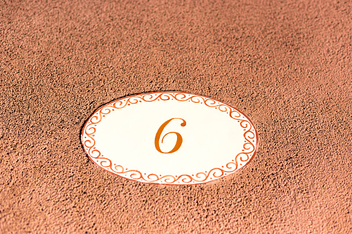 Ceramic Number 6 Street Address Tile on Brown Wall Background. Copy space available.
