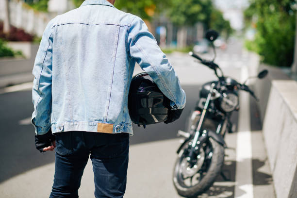 Man with motorcycle helmet Man in denim jacket standing with motorcycle helmet, view from the back biker photos stock pictures, royalty-free photos & images