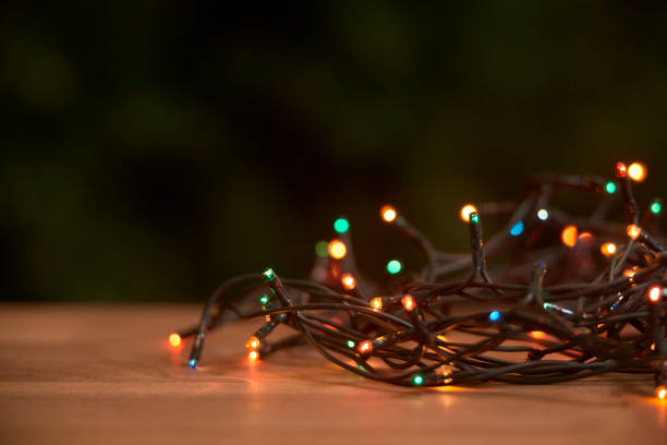 istock Christmas scene: lighted light cord with different colored lights shining on a wooden surface 1282589789