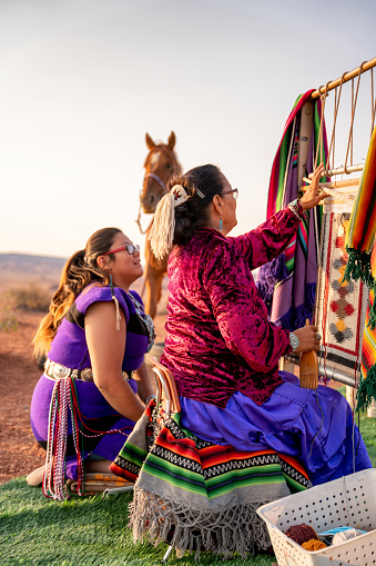 Una abuela navajo enseñando a su nieta La tradición de tejer en un telar de tejedores antiguos, con su traje tradicional navajo photo