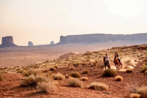 Photo of Four Young Native American Navajo Brothers and Sisters Riding their Horses Bareback in the Northern Arizona Monument Valley Tribal Park At Dusk Together