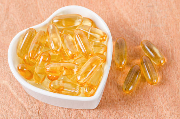 istock Fish oil capsules in white cup on wooden 1282590849