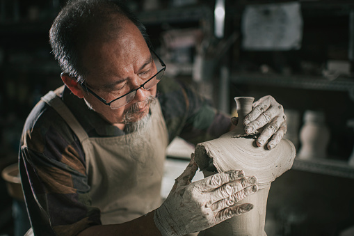 asian chinese senior man clay artist working in his studio joining 2 sculpture