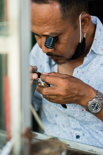Jakarta, Indonesia - October 24, 2020: The technician is repairing of mechanical wristwatch at Senen market in Jakarta. Selective focus.