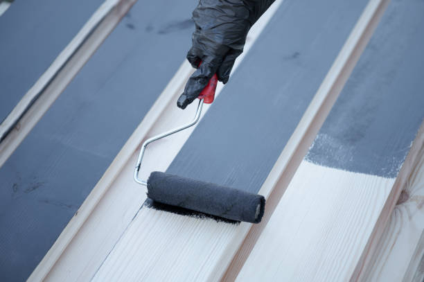 istock A man or woman wearing protective gloves, using a roller, paints the Board black, the view from above is very close. 1282607723