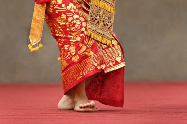 Asian travel background. Beautiful Balinese dancer woman in traditional Sarong costume dancing Legong dance. Legs movements. Arts, culture of Indonesian people, Bali island festivals.