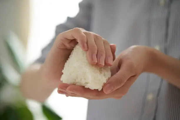 Hands of a young woman holding a rice ball