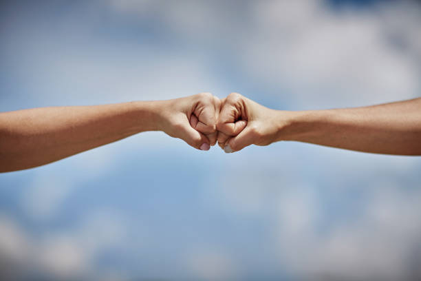 Two Hispanic young women bumping fists