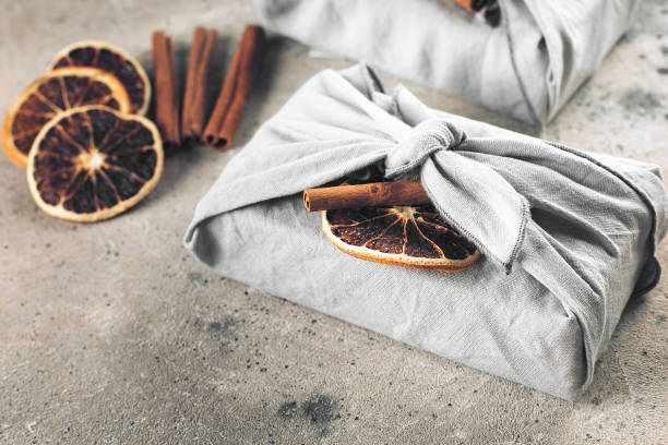 holiday eco-friendly fabric reusable gift packaging with dry orange and cinnamon. zero waste concept - gift orange green package imagens e fotografias de stock