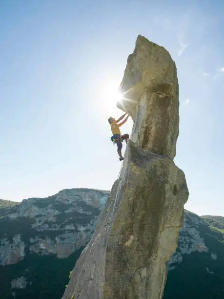 Photo of Mountaineer climbs up mountain peak in the morning