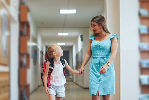 Mom accompanies daughter in the school corridor.