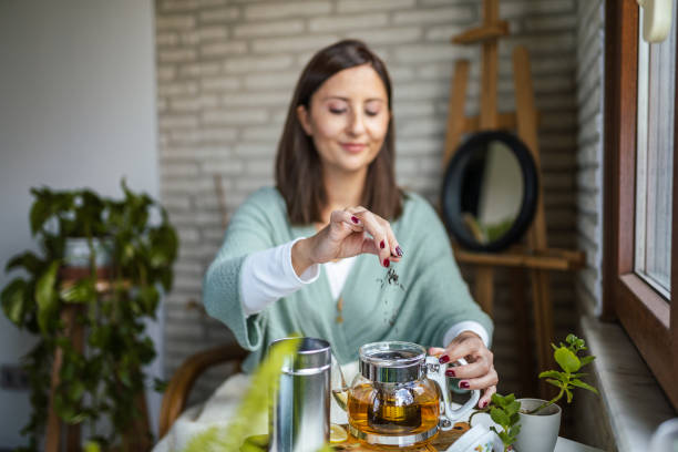 giovane donna che prepara il suo tè invernale e accoglie il nuovo giorno - tè alle erbe foto e immagini stock