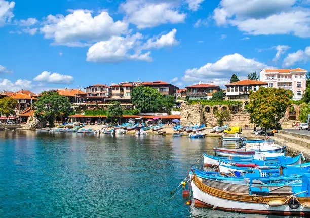 Boats mooring on sea in Nessebar, Bulgaria. Summer sunny landscape with moored woods boat at quay by blue sky