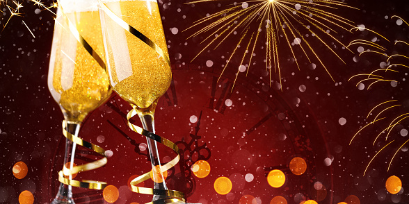 Two glasses of champagne with gold ribbons on red background. Christmas celebration