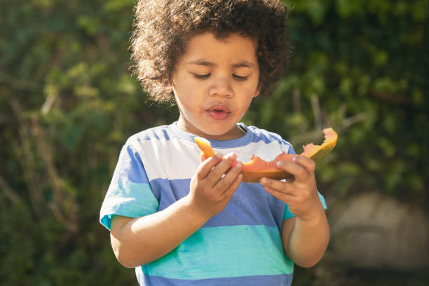 istock Cute boy eating a papaya on a sunny day 1282632014