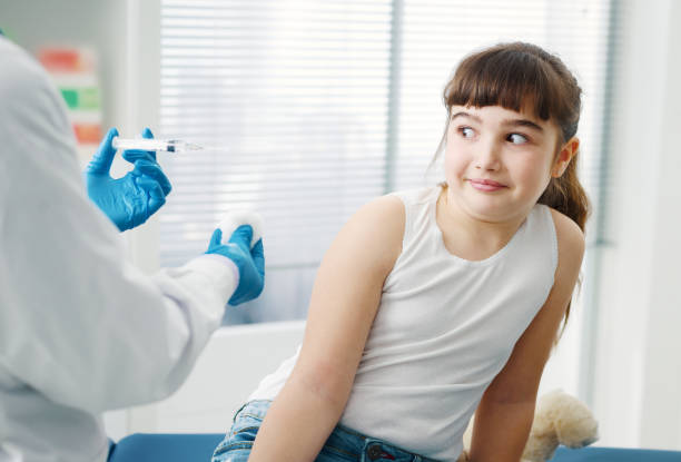 врач, дать инъекцию испуганной молодой девушке - injecting flu virus cold and flu doctors office стоковые фото и изображения