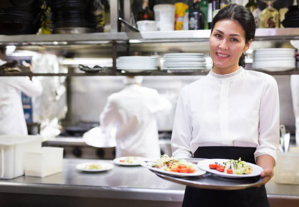 istock Confident waitress holding cooked meals in restaurant kitchen 1282636142