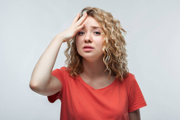 jolie fille blonde dans le t-shirt occasionnel fait une erreur. concept pensif. plan de studio, fond blanc - beauty beautiful tired blond hair photos et images de collection