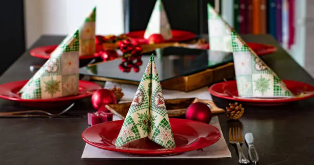 Christmas decoration on a dinner table with red plates on a dark table