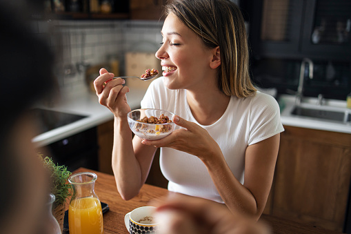 Portrait of a beautiful women enjoying breakfast. She is eating cereals with her eyes closed