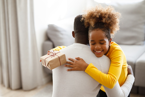 An African girl is hugging her father with a huge smile after getting a Christmas present.