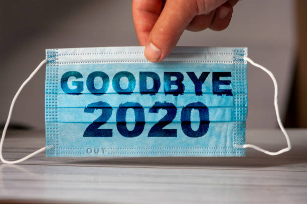 la main tient un masque médical et protecteur avec le mot goodbye 2020. concept de quarantaine de coronavirus. prévenir ou arrêter la propagation du covide-19 dans le monde entier. - 2020 photos et images de collection