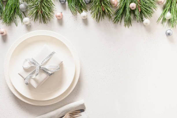 istock Christmas table setting with white gift and silver decorations on white. 1282637873
