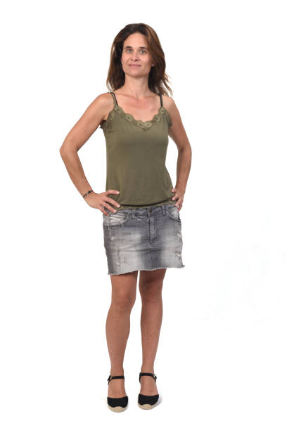 woman in a denim skirt on white background, front view of the full portrait of a woman in a denim skirt on white background, hands on hip older women short skirts stock pictures, royalty-free photos & images
